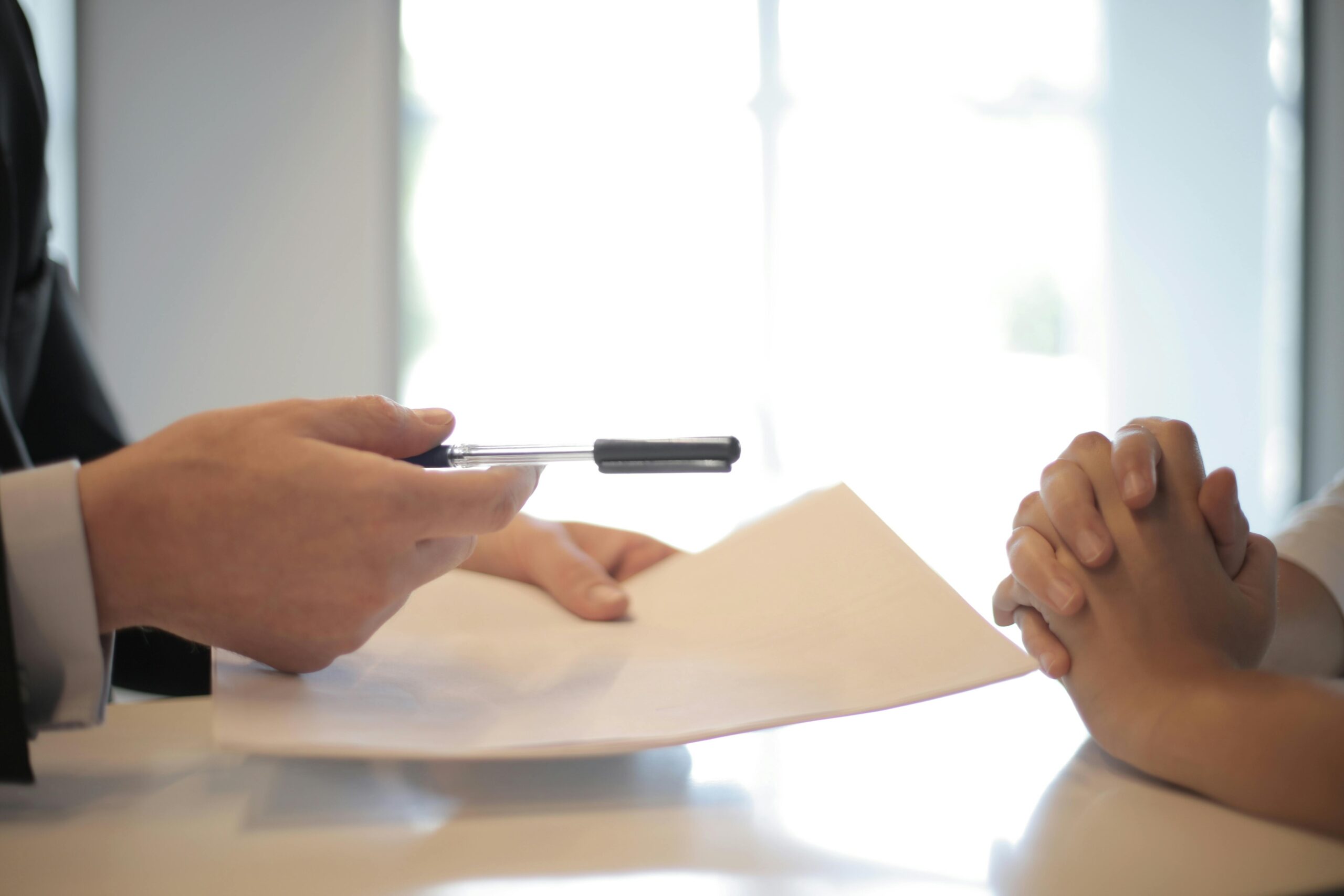 Someone handing off an application and pen to sign